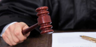 Judges hand holding gavel next to documents.