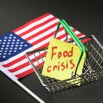 A small shopping basket with a sticky note reading 'Food crisis' next to an American flag