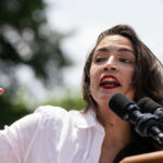 Alexandria Ocasio-Cortez speaking at an outdoor event.