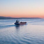 Cargo ship navigating through calm waters at sunset