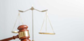 A wooden gavel in front of a balance scale symbolizing justice