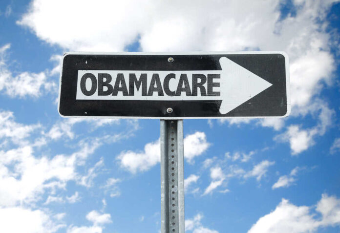 Directional sign pointing towards Obamacare against a blue sky