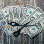 Trump Slashes Biden Loans Scissors placed on a spread of various U.S. dollar bills