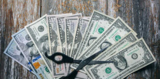 Scissors placed on a spread of various U.S. dollar bills