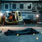 Police investigation at a crime scene with a covered body and evidence markers