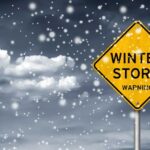 Winter Storm PARALYZES Nation — 10,000 Flights GONE A yellow warning sign indicating a winter storm amidst falling snow