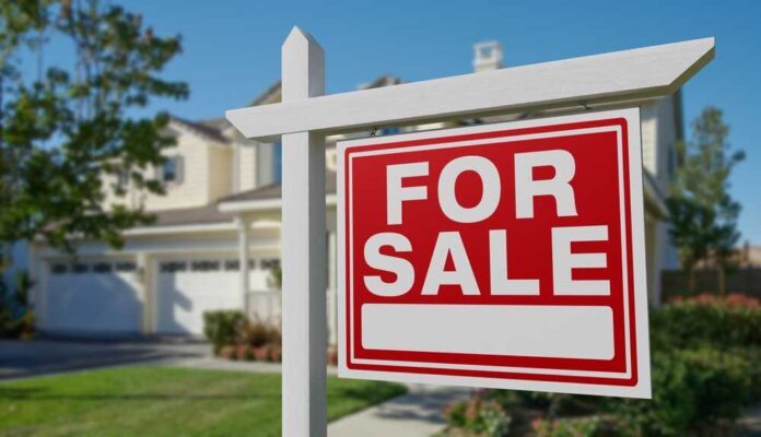shutterstock_2487826759.jpg A 'For Sale' sign in front of a house
