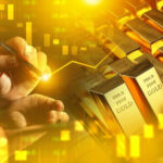 Hand writing near stacked gold bars and charts