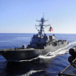 Warship with American flag sailing in the ocean.