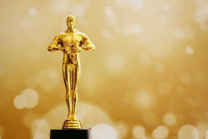 Golden Oscar trophy against a sparkling gold background.