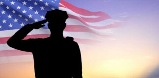 Silhouette of soldier saluting in front of flag