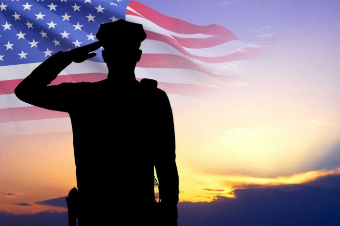 shutterstock_2461746929.jpg Silhouette of soldier saluting in front of flag