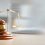 A wooden gavel and scales of justice on a desk