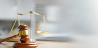 A wooden gavel and scales of justice on a desk