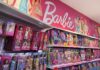 Shelves filled with various Barbie dolls and accessories in a toy store