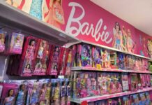 Shelves filled with various Barbie dolls and accessories in a toy store