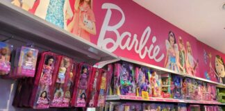 Shelves filled with various Barbie dolls and accessories in a toy store