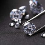 Close-up of diamonds being held with tweezers on a dark background