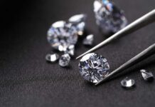 Close-up of diamonds being held with tweezers on a dark background