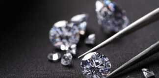 Close-up of diamonds being held with tweezers on a dark background