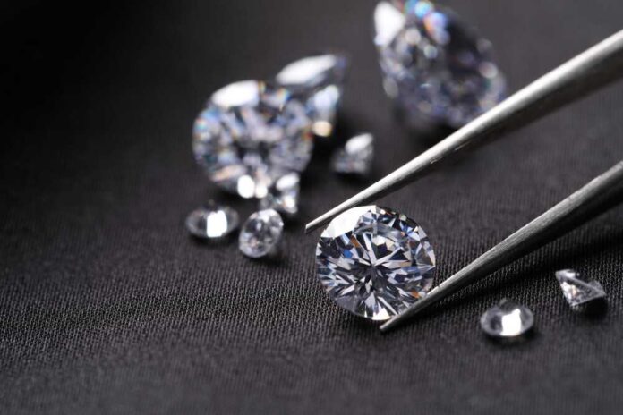 Close-up of diamonds being held with tweezers on a dark background