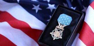 A military medal displayed on a black box with an American flag background
