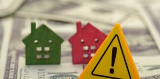 Colorful house models and a warning sign on dollar bills