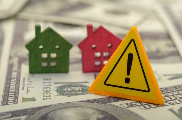 Colorful house models and a warning sign on dollar bills