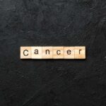 Wooden letters spelling the word 'Cancer' on a black textured background