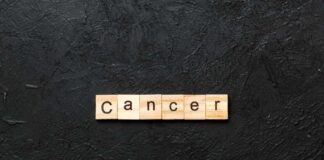 Wooden letters spelling the word 'Cancer' on a black textured background