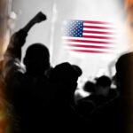 Silhouetted crowd with raised fists in front of an American flag and flames