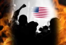 Silhouetted crowd with raised fists in front of an American flag and flames