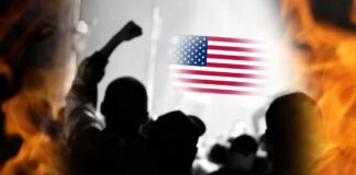 Silhouetted crowd with raised fists in front of an American flag and flames