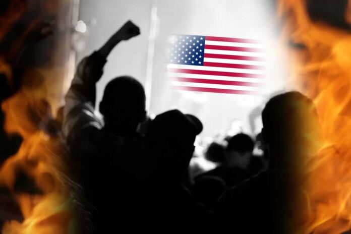 Silhouetted crowd with raised fists in front of an American flag and flames