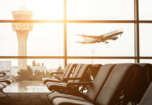 View of an airport terminal with an airplane taking off in the background