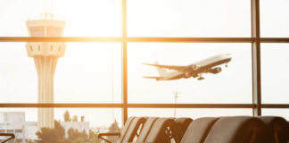 View of an airport terminal with an airplane taking off in the background