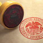 A wooden stamp with the Federal Reserve seal on a brown paper background