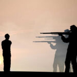 Silhouette of soldiers firing squadding a person