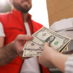 A delivery person handing over cash for pizza boxes