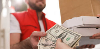 A delivery person handing over cash for pizza boxes