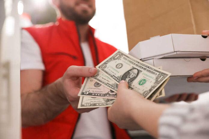 A delivery person handing over cash for pizza boxes