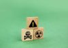 Wooden blocks displaying hazard symbols including a skull, radiation, and an exclamation mark