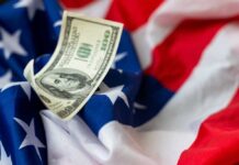 Trump’s $50 Billion Demand — Taxpayers on Hook A hundred dollar bill resting on an American flag