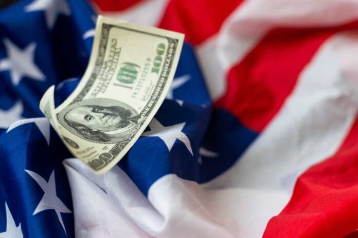 A hundred dollar bill resting on an American flag