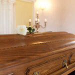 Congressman DIES Mid-Campaign A wooden casket with a white rose placed on top in a solemn setting