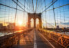 Brooklyn Bridge at sunset with city skyline background.