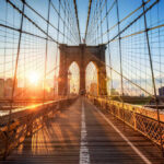 Brooklyn Bridge at sunset with city skyline background.