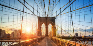 Brooklyn Bridge at sunset with city skyline background.