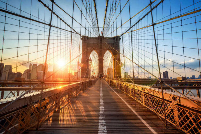 Brooklyn Bridge at sunset with city skyline background.