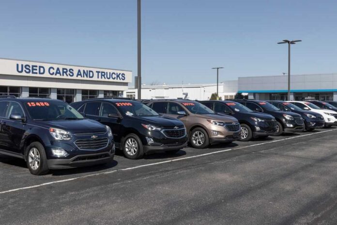 Row of used cars for sale at a dealership with price tags displayed